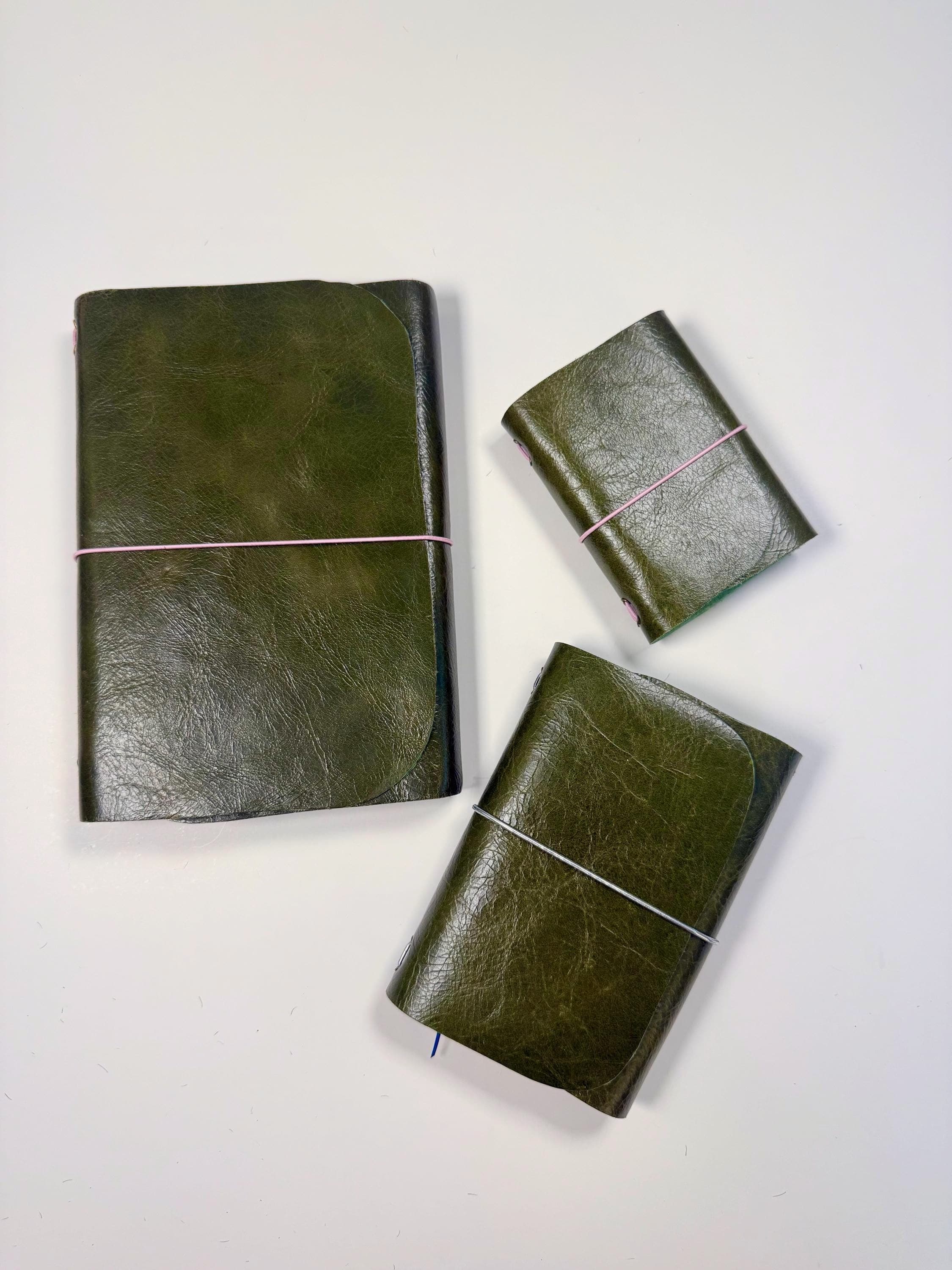 Three olive leather devotional companions in A5, A6 and A7, laid out from above
