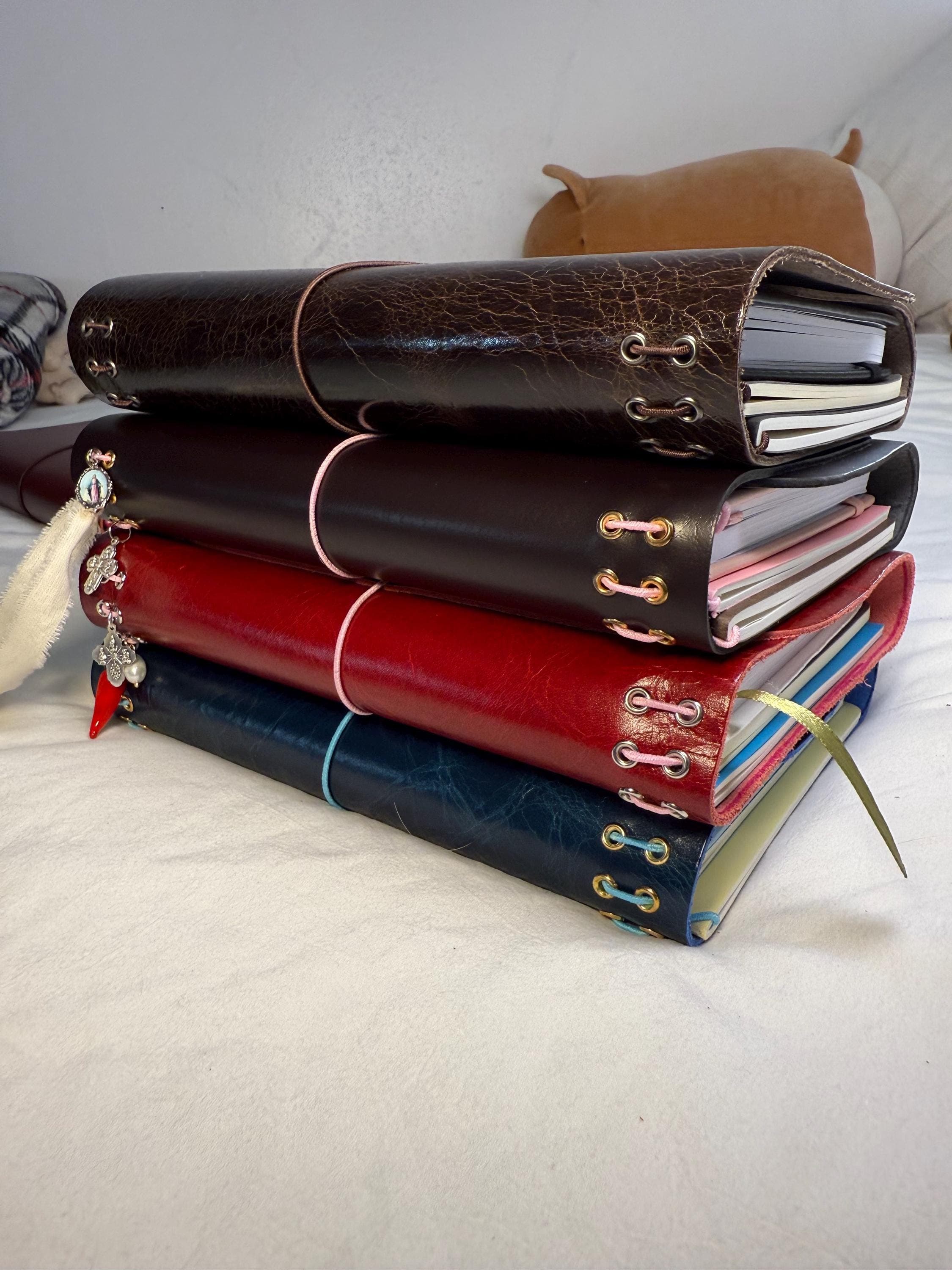 Four devotional companions stacked, showing the grommets and charms along each spine